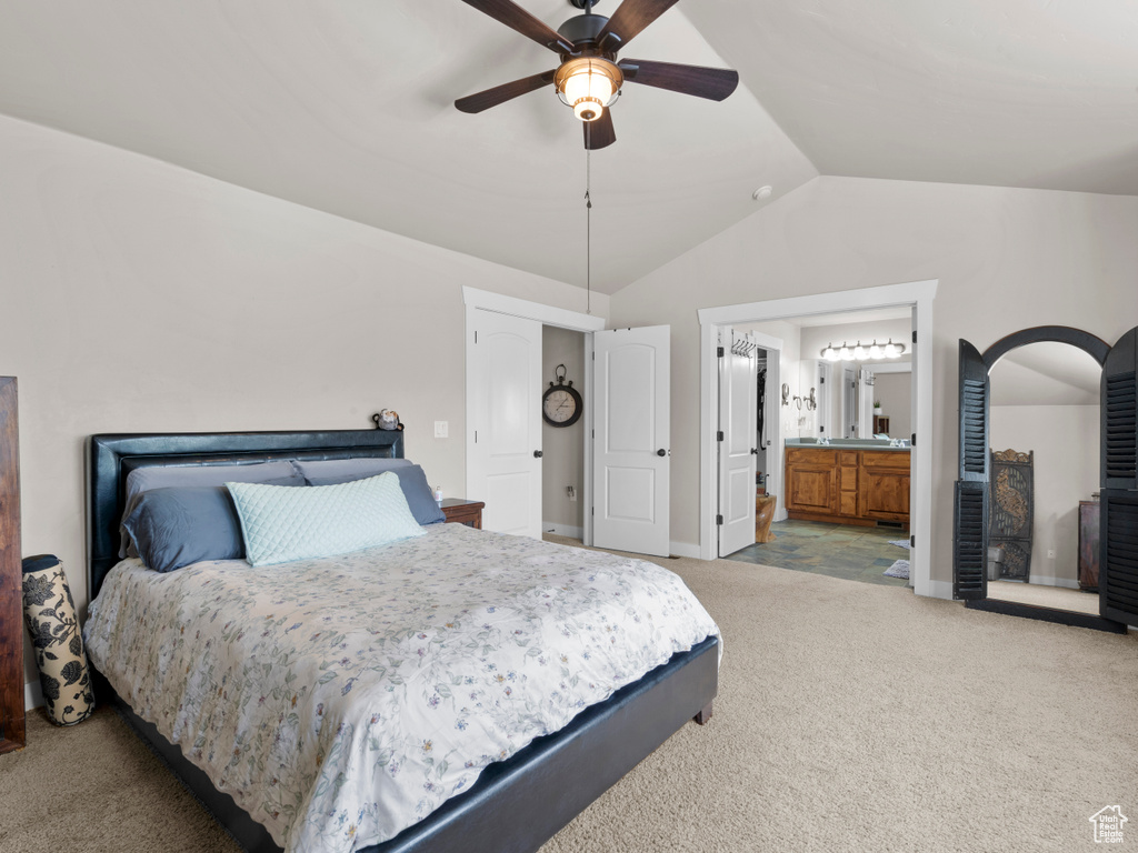 Bedroom featuring vaulted ceiling, baseboards, light colored carpet, ceiling fan, and ensuite bathroom