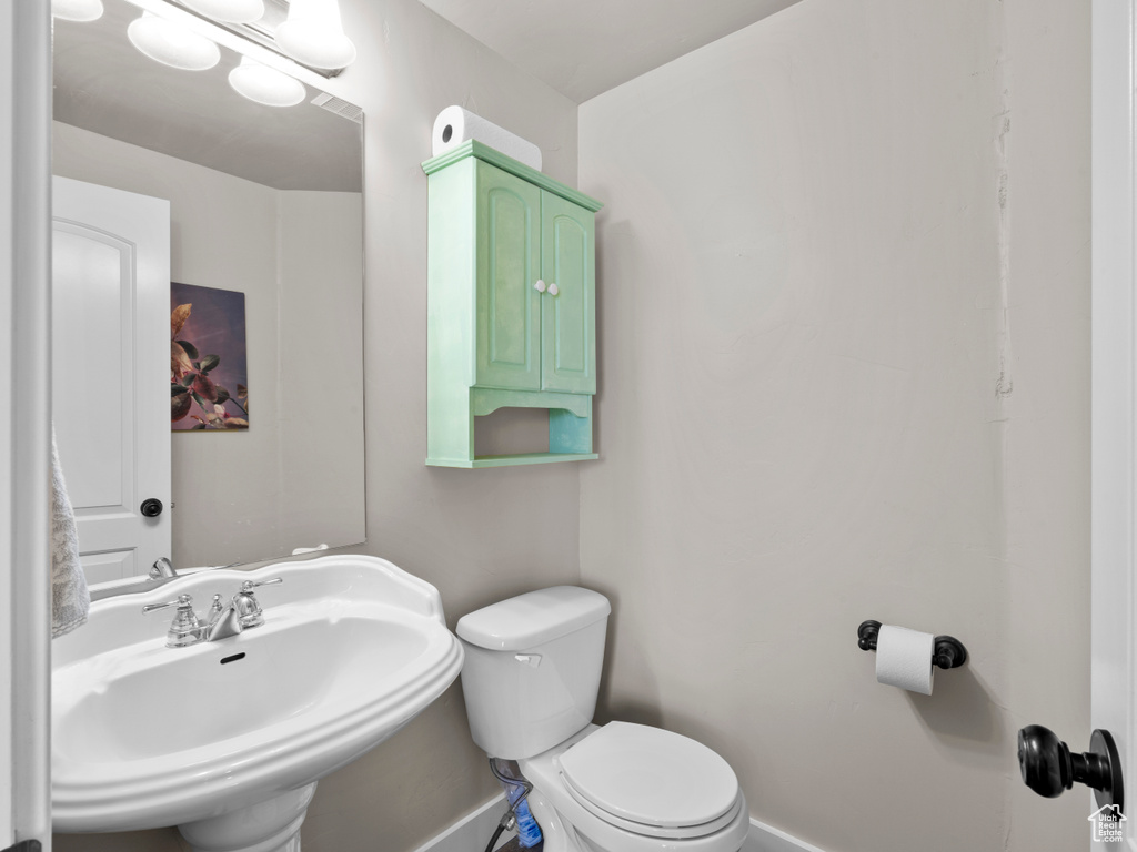 Half bathroom featuring toilet, a sink, and baseboards