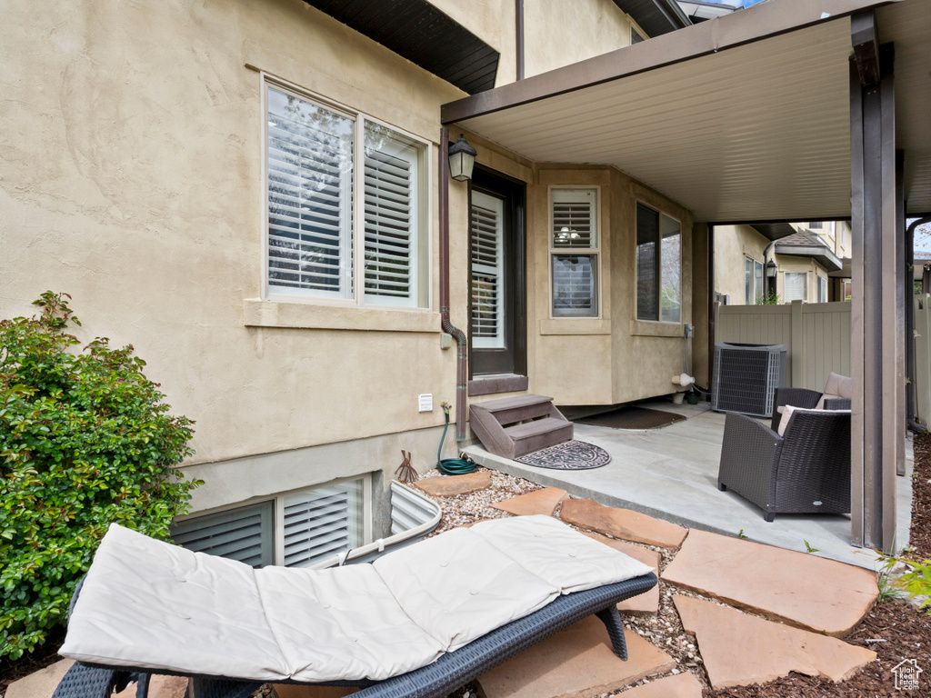 View of patio with fence, entry steps, and central AC unit