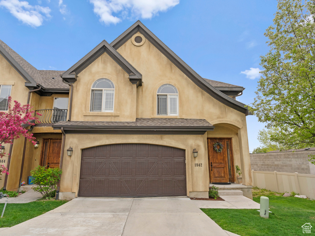 View of front facade featuring concrete driveway, fence, a garage, and stucco siding