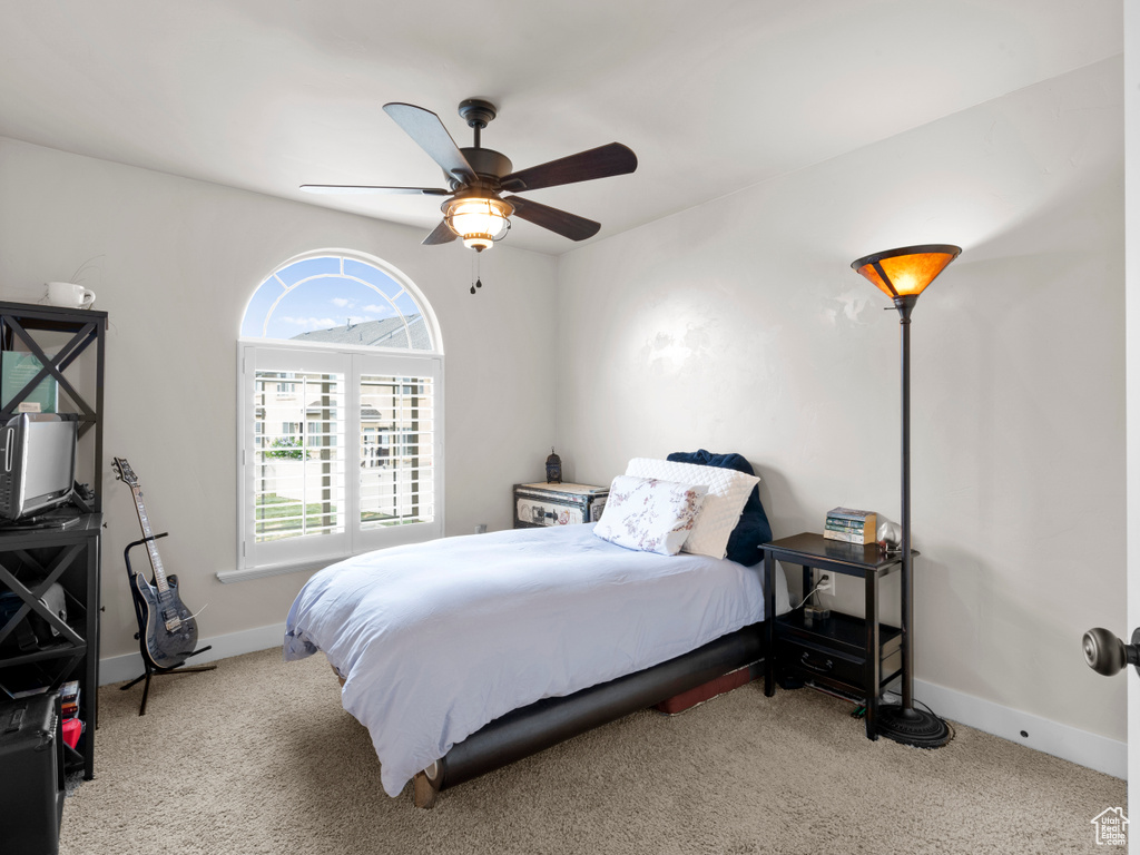 Carpeted bedroom with ceiling fan and baseboards