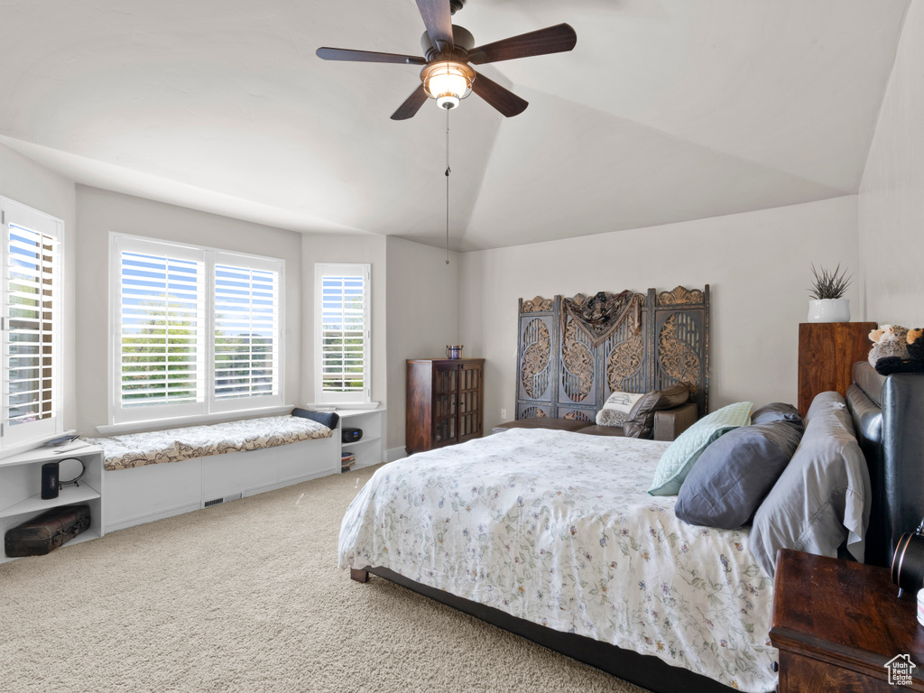 Bedroom with ceiling fan, vaulted ceiling, multiple windows, and carpet