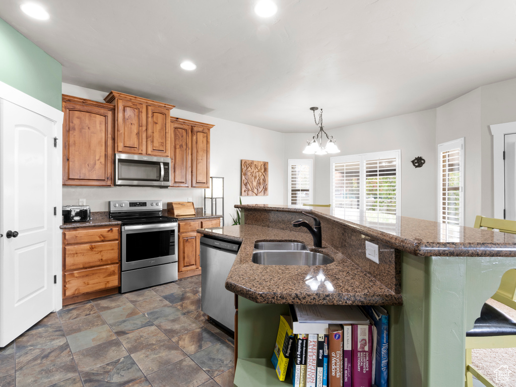 Kitchen with a sink, recessed lighting, an inviting chandelier, an island with sink, and appliances with stainless steel finishes