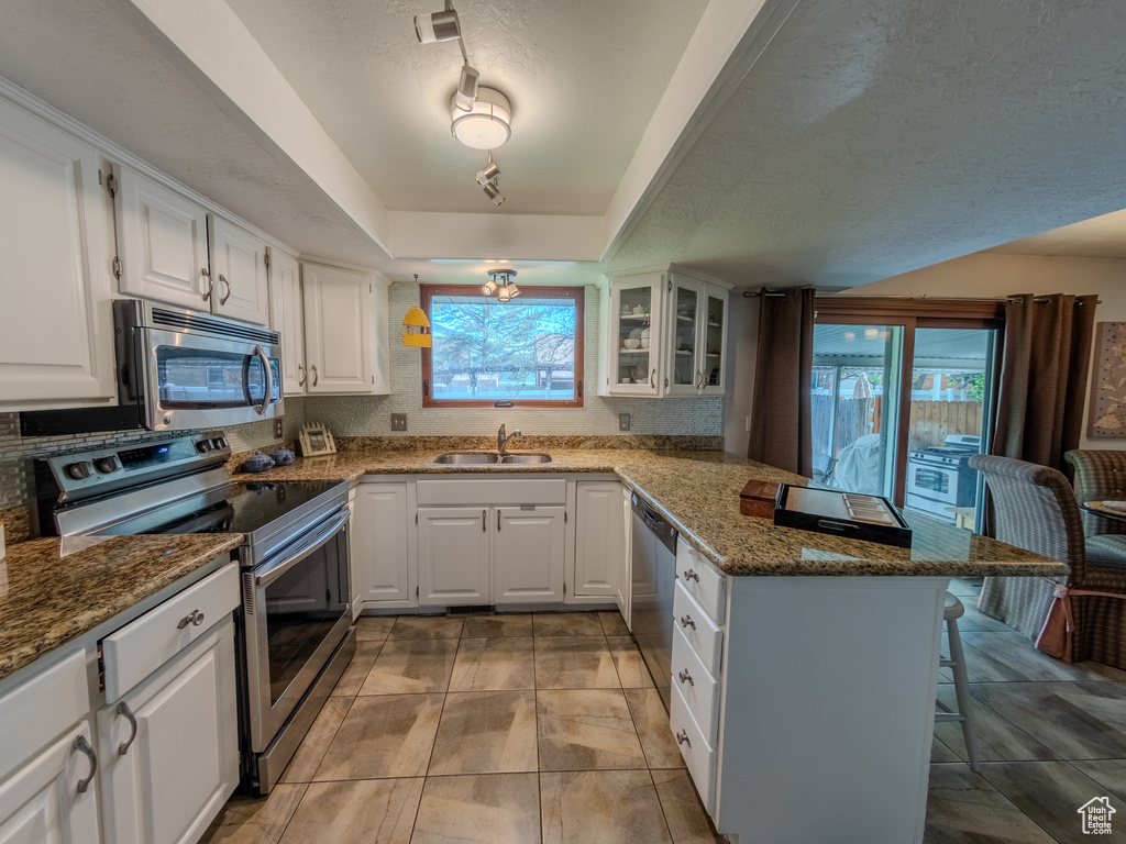 Kitchen with stainless steel appliances, plenty of natural light, a kitchen breakfast bar, and a peninsula