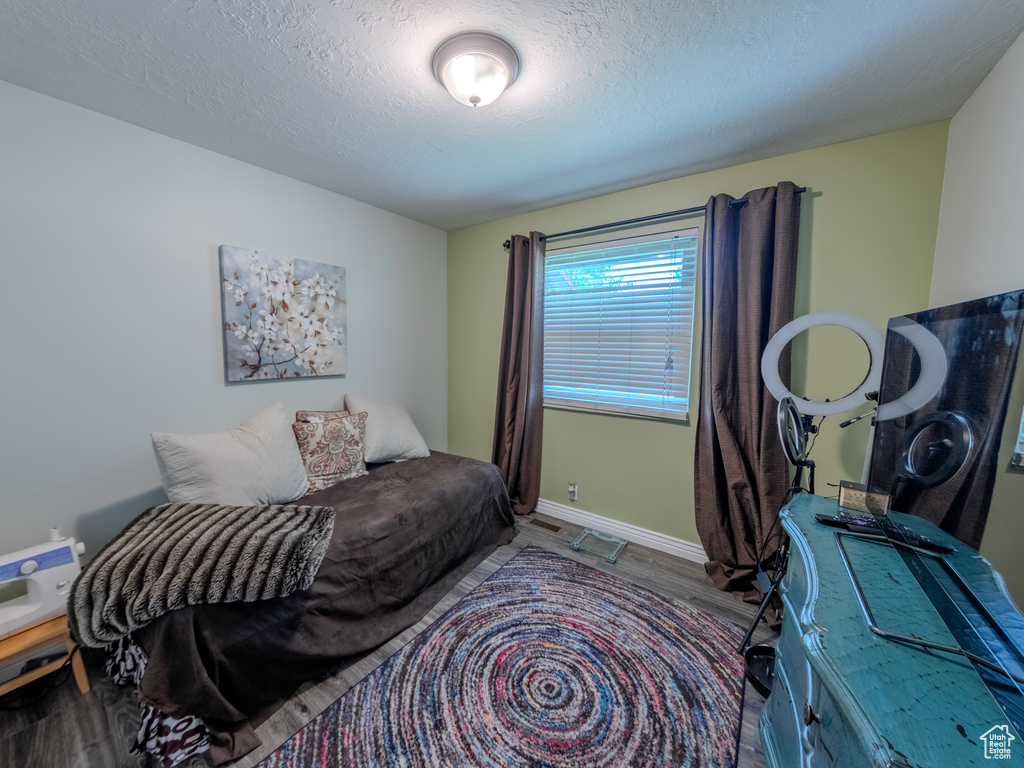 Bedroom featuring a textured ceiling, baseboards, and wood finished floors