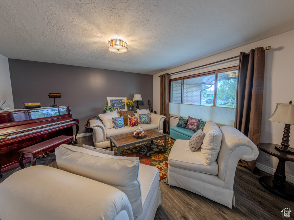 Living room featuring baseboards, a textured ceiling, and wood finished floors
