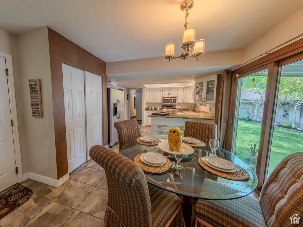 Dining space featuring light tile patterned floors, baseboards, and a chandelier
