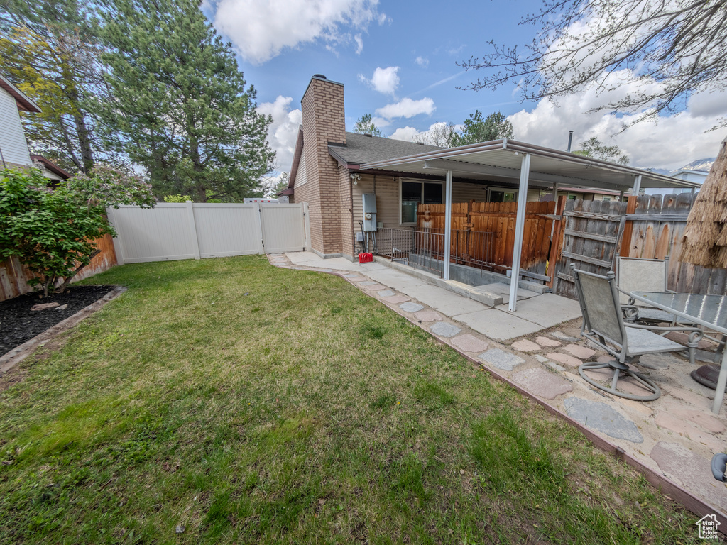 Rear view of property with a patio, a fenced backyard, a yard, and a chimney