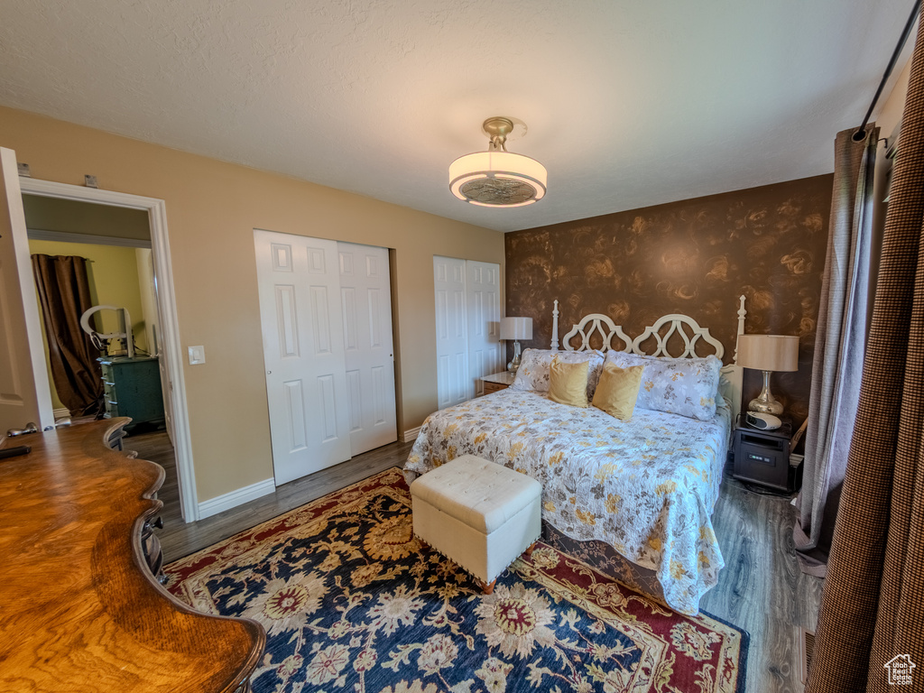 Bedroom with two closets, baseboards, and wood finished floors
