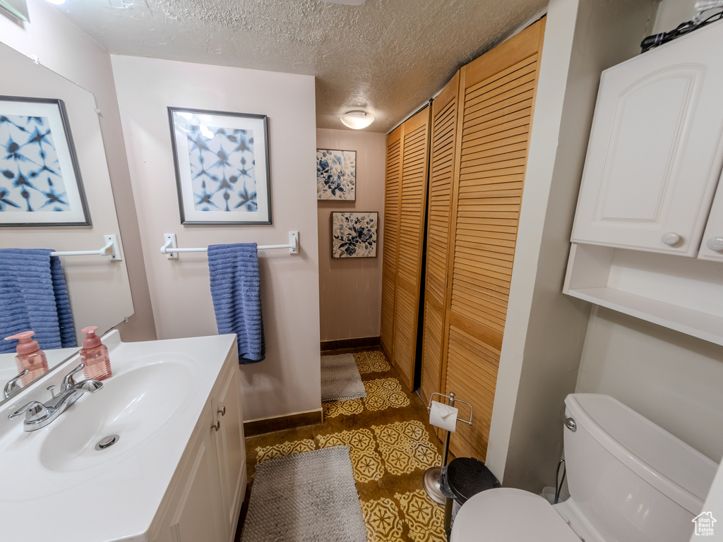 Bathroom with vanity, tile patterned flooring, toilet, and a textured ceiling