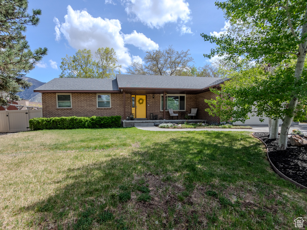Single story home featuring brick siding, a garage, a gate, and a front lawn