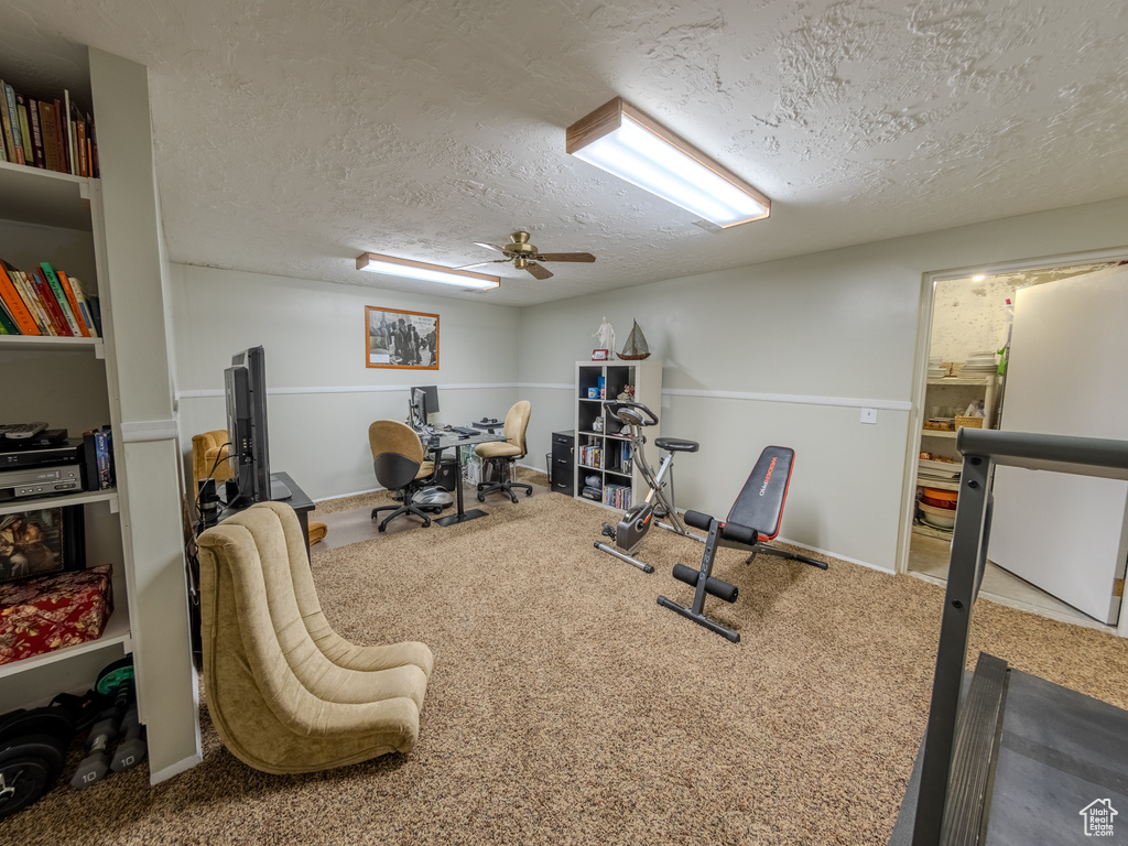 Workout area with carpet floors, a ceiling fan, and a textured ceiling