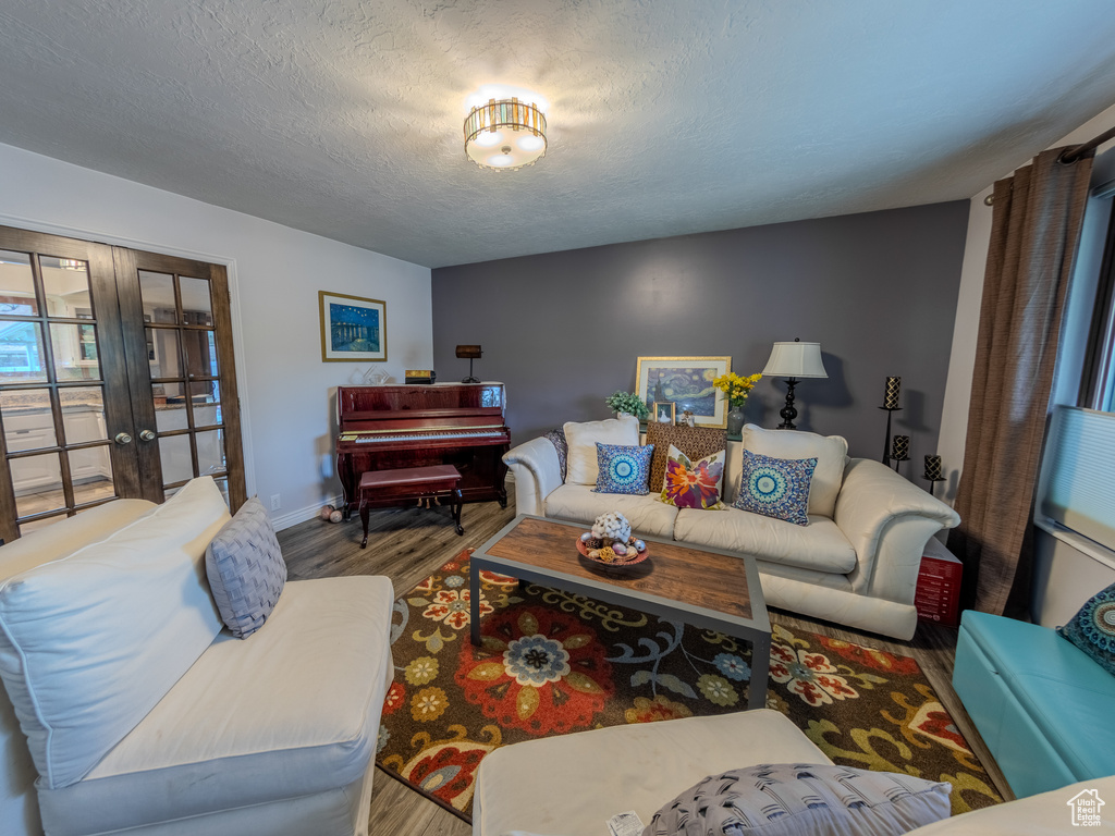 Living room featuring baseboards, a textured ceiling, wood finished floors, and french doors