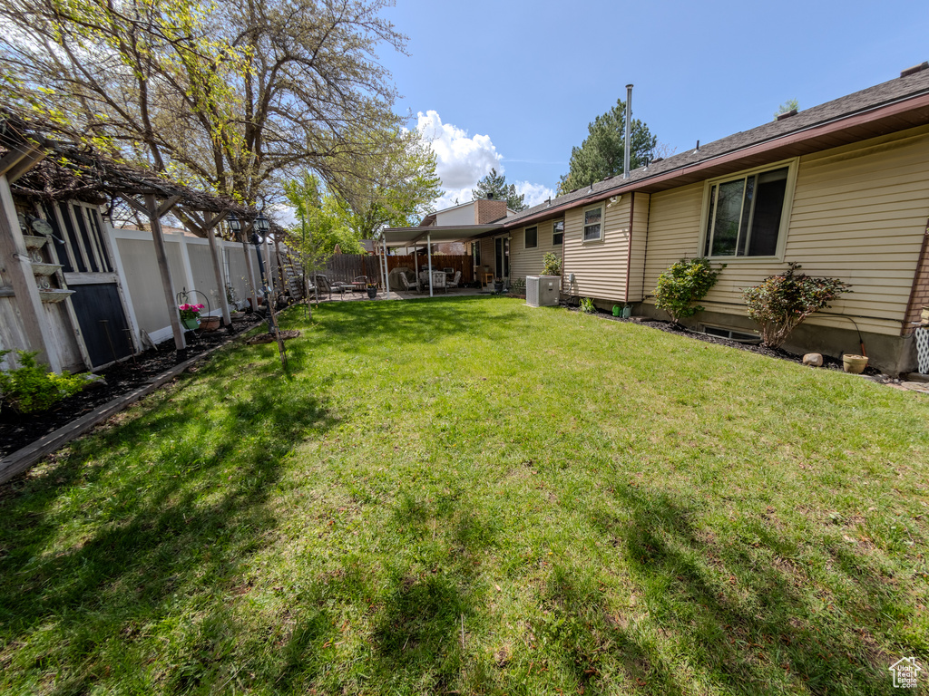 View of yard with a fenced backyard, central AC, and a patio area