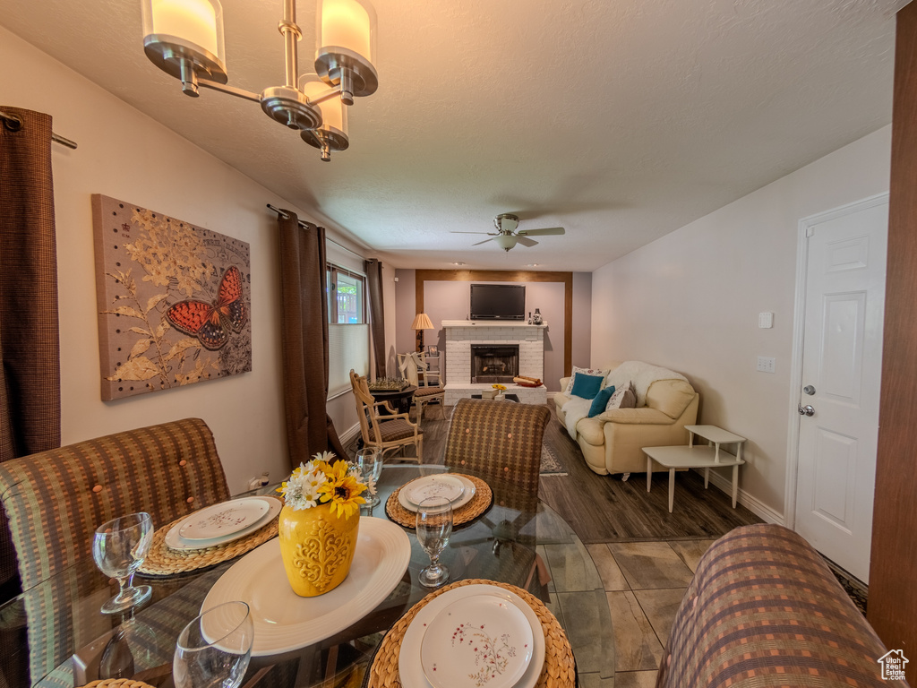Dining space with baseboards, ceiling fan with notable chandelier, and a brick fireplace