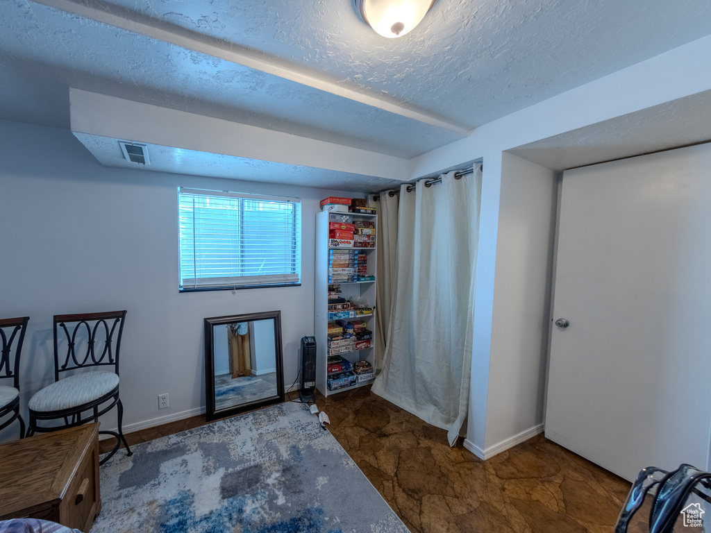Living area featuring a textured ceiling, visible vents, and baseboards