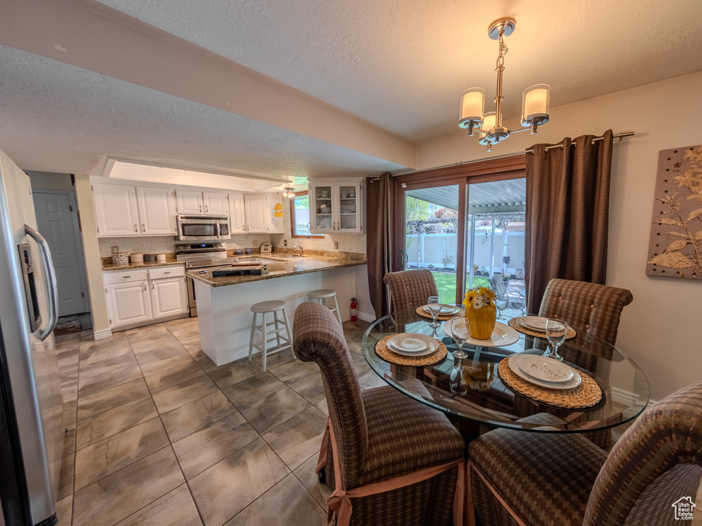 Dining space featuring baseboards, a textured ceiling, an inviting chandelier, and light tile patterned floors