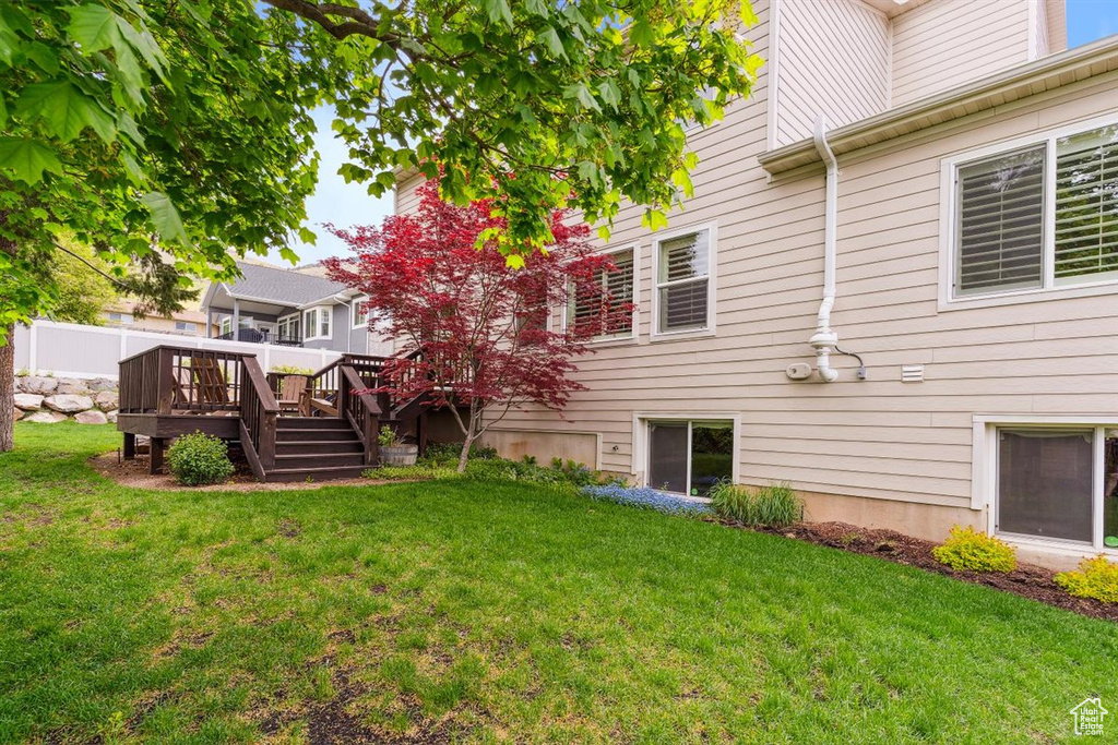Back of property featuring a lawn and a wooden deck