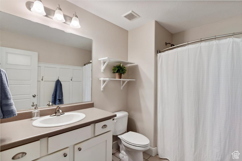 Full bathroom with visible vents, tile patterned flooring, curtained shower, vanity, and toilet