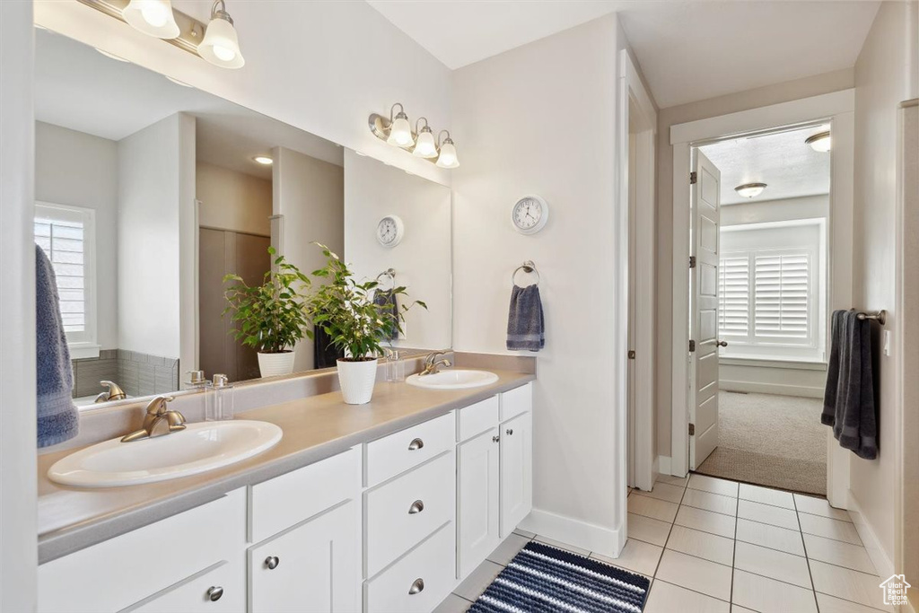Full bathroom with double vanity, baseboards, a sink, and tile patterned flooring