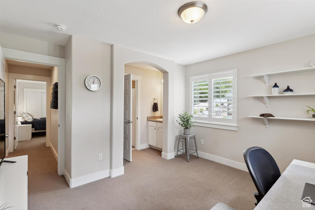 Office area featuring light colored carpet, arched walkways, and baseboards