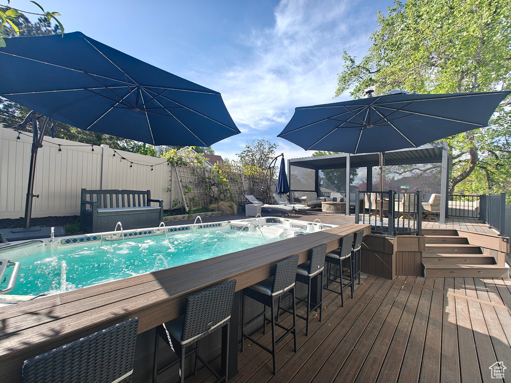 View of pool with a fenced backyard, outdoor dry bar, and a deck