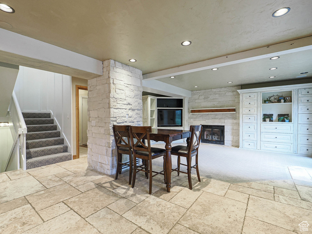 Dining area with a stone fireplace, stone tile floors, recessed lighting, stairs, and ornate columns