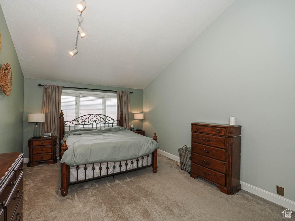 Carpeted bedroom featuring baseboards and vaulted ceiling