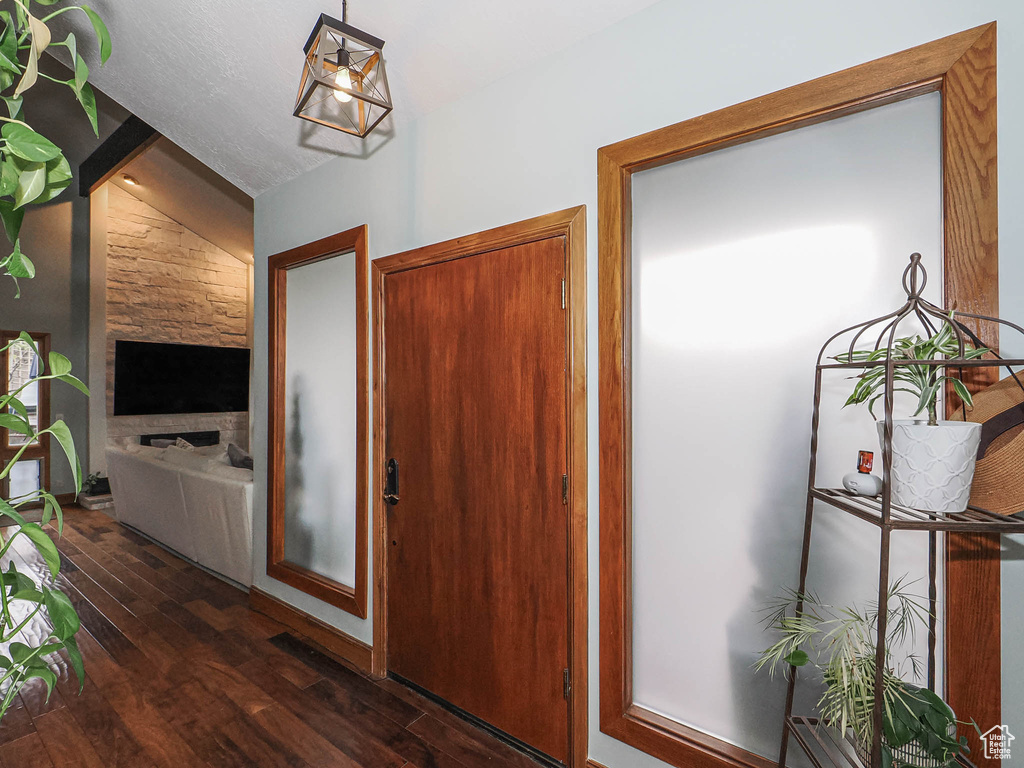 Entrance foyer with lofted ceiling with beams, a stone fireplace, and dark wood-type flooring