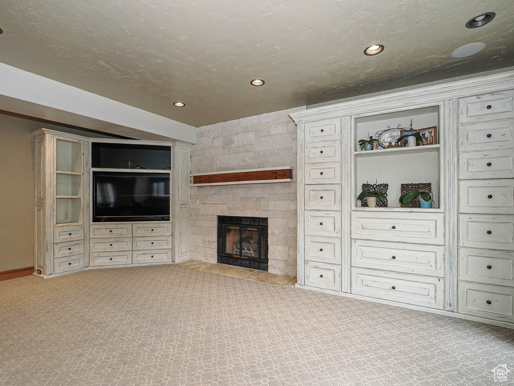 Unfurnished living room featuring carpet flooring, recessed lighting, and a stone fireplace