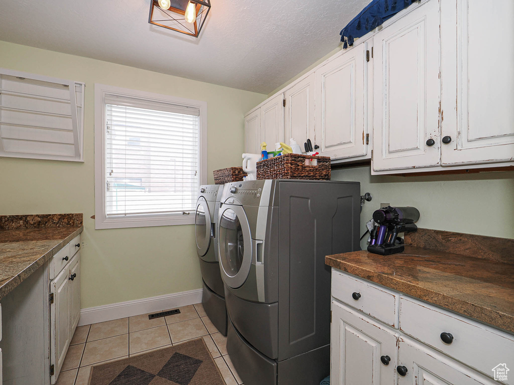 Laundry room featuring cabinet space, separate washer and dryer, baseboards, light tile patterned floors, and visible vents