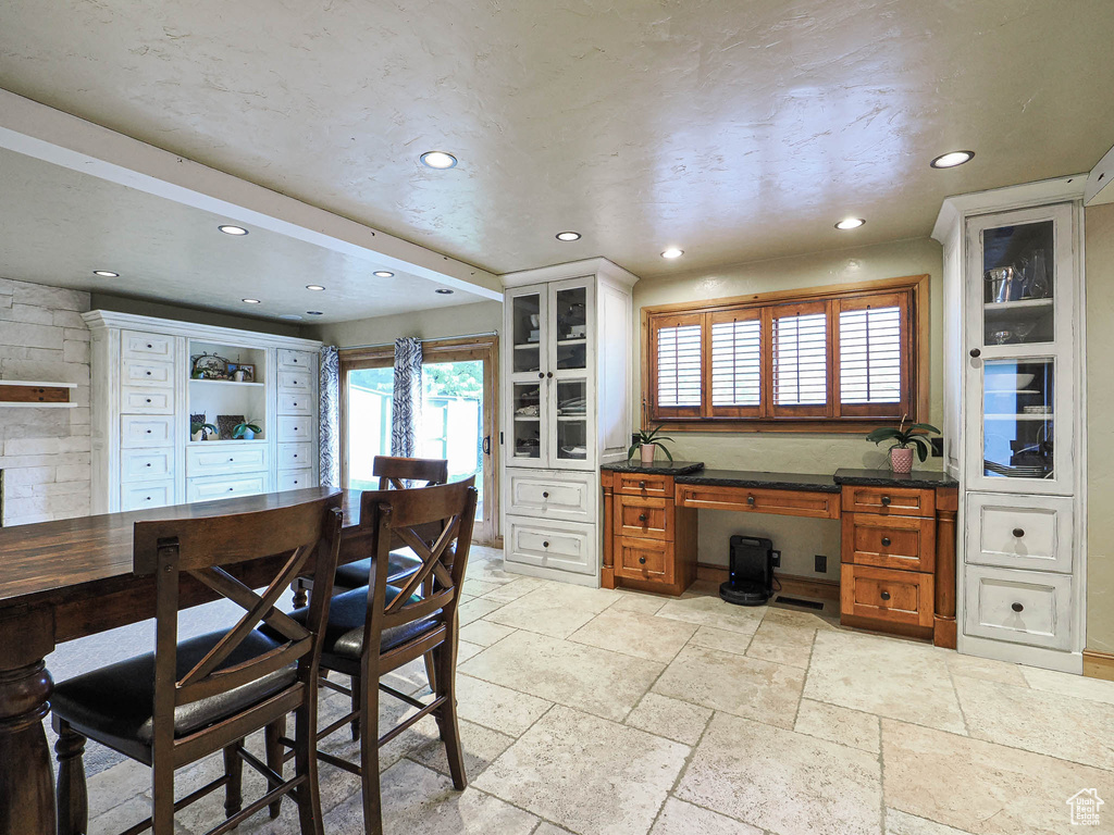 Kitchen featuring glass insert cabinets, brown cabinets, recessed lighting, and stone tile flooring