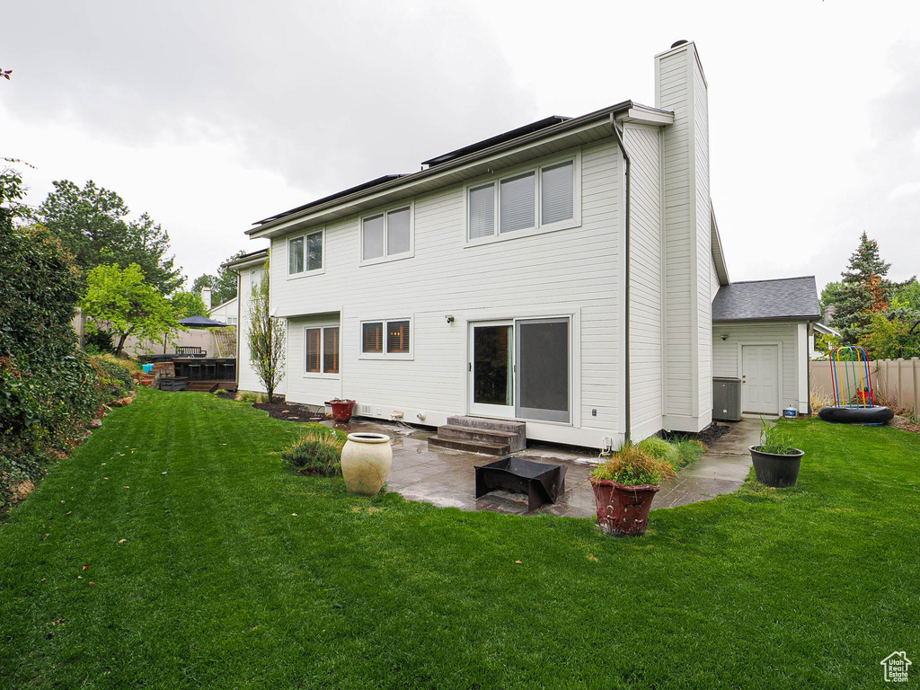 Back of house featuring fence, entry steps, a chimney, a lawn, and a patio