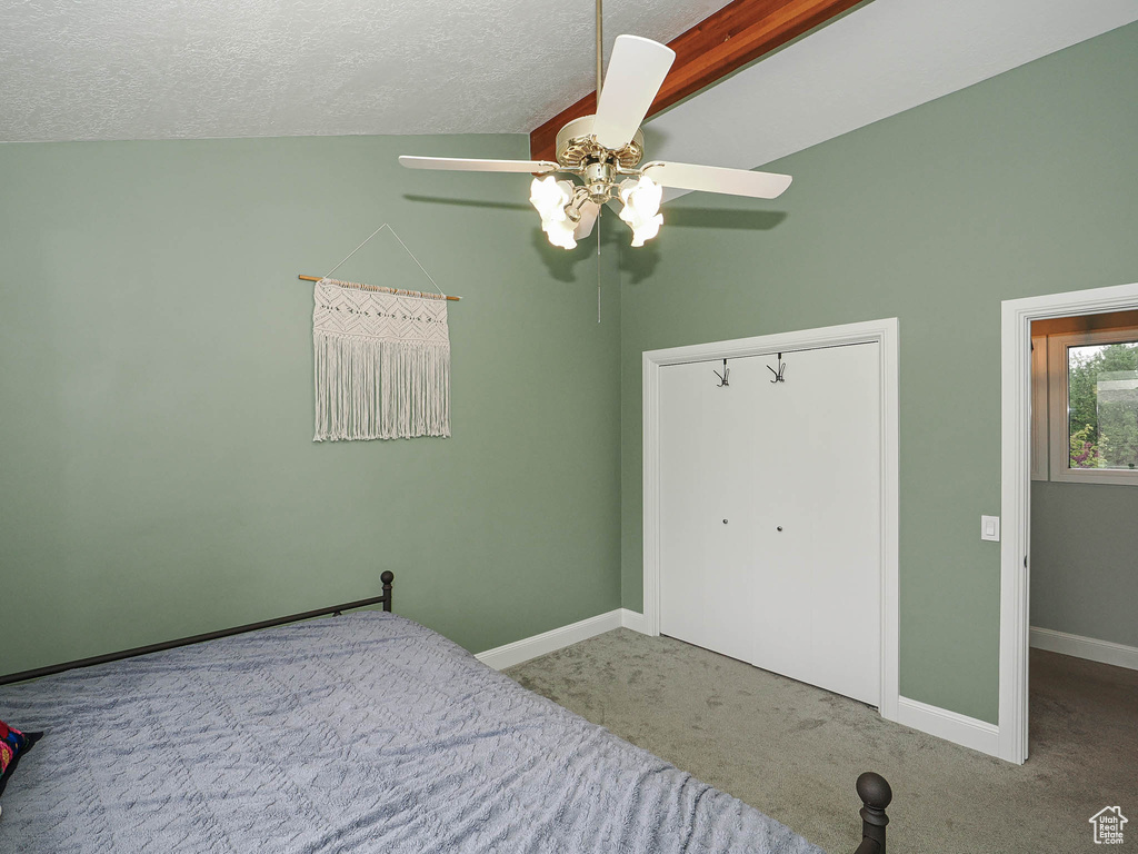 Carpeted bedroom featuring a textured ceiling, baseboards, a ceiling fan, and lofted ceiling