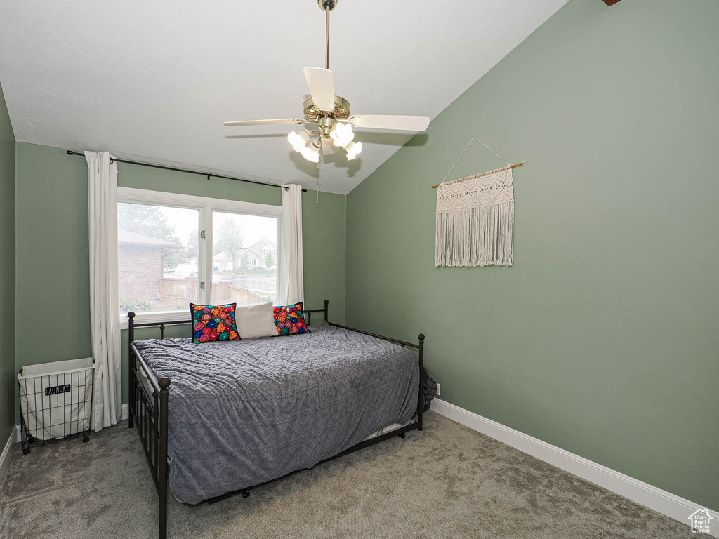 Carpeted bedroom with a ceiling fan, baseboards, and vaulted ceiling