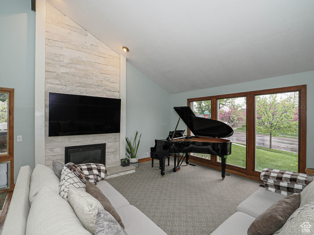 Carpeted living room with a stone fireplace and lofted ceiling
