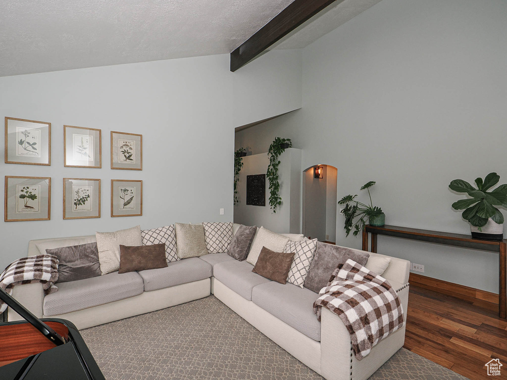Living area with baseboards, lofted ceiling with beams, and wood finished floors