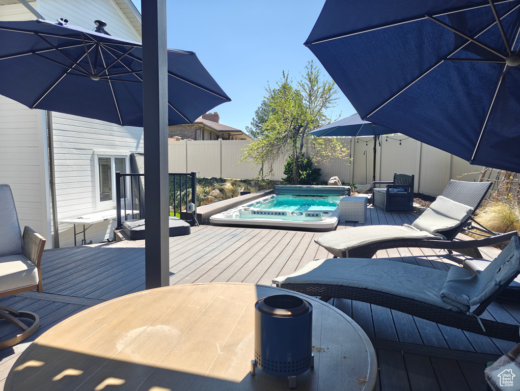 Wooden deck with a fenced backyard, outdoor dining space, and hot tub deck surround