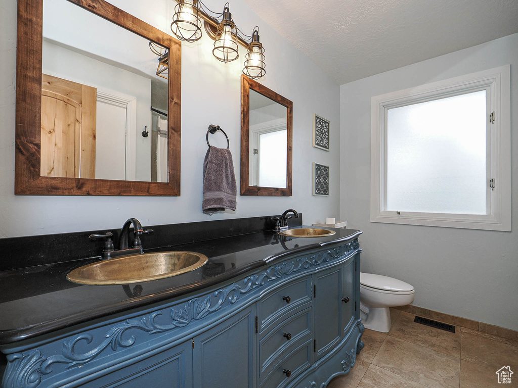 Bathroom featuring a sink, toilet, double vanity, and visible vents