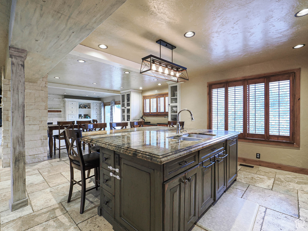Kitchen with recessed lighting, a sink, an island with sink, and stone tile floors
