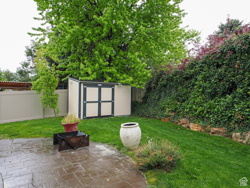 View of yard featuring an outdoor structure, a patio, a fenced backyard, and a storage unit
