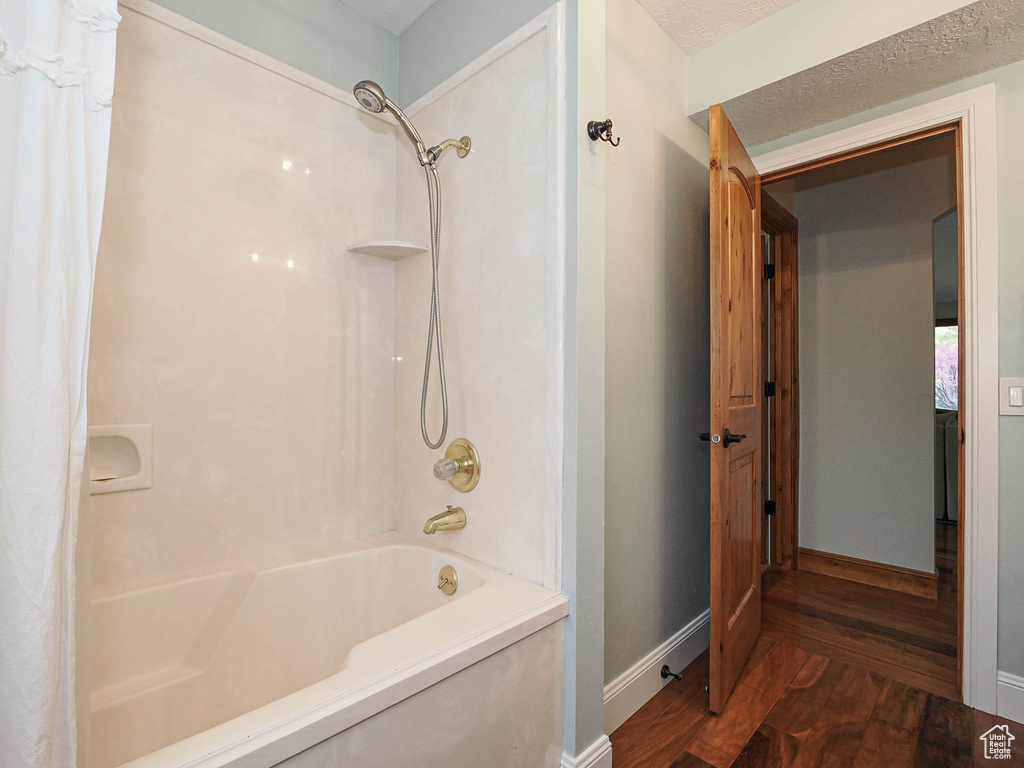 Bathroom with baseboards, wood finished floors, and shower / bath combo