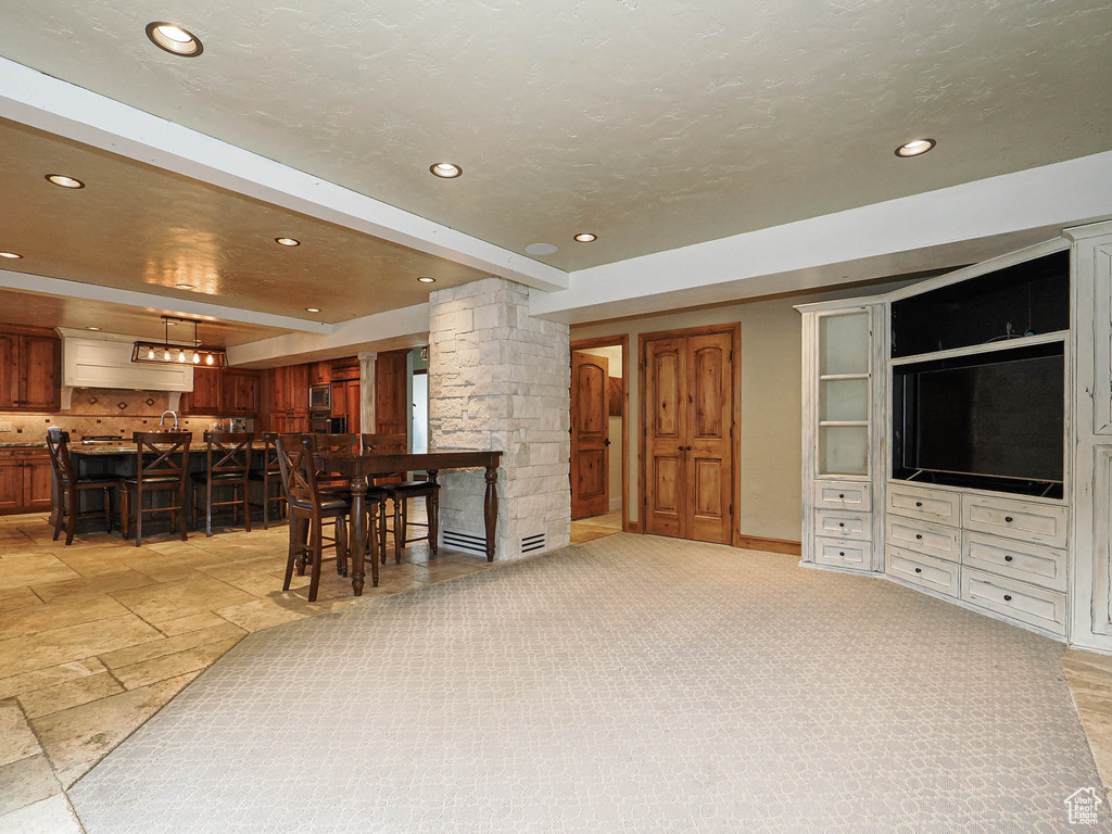 Living room with recessed lighting, wet bar, decorative columns, and stone tile flooring