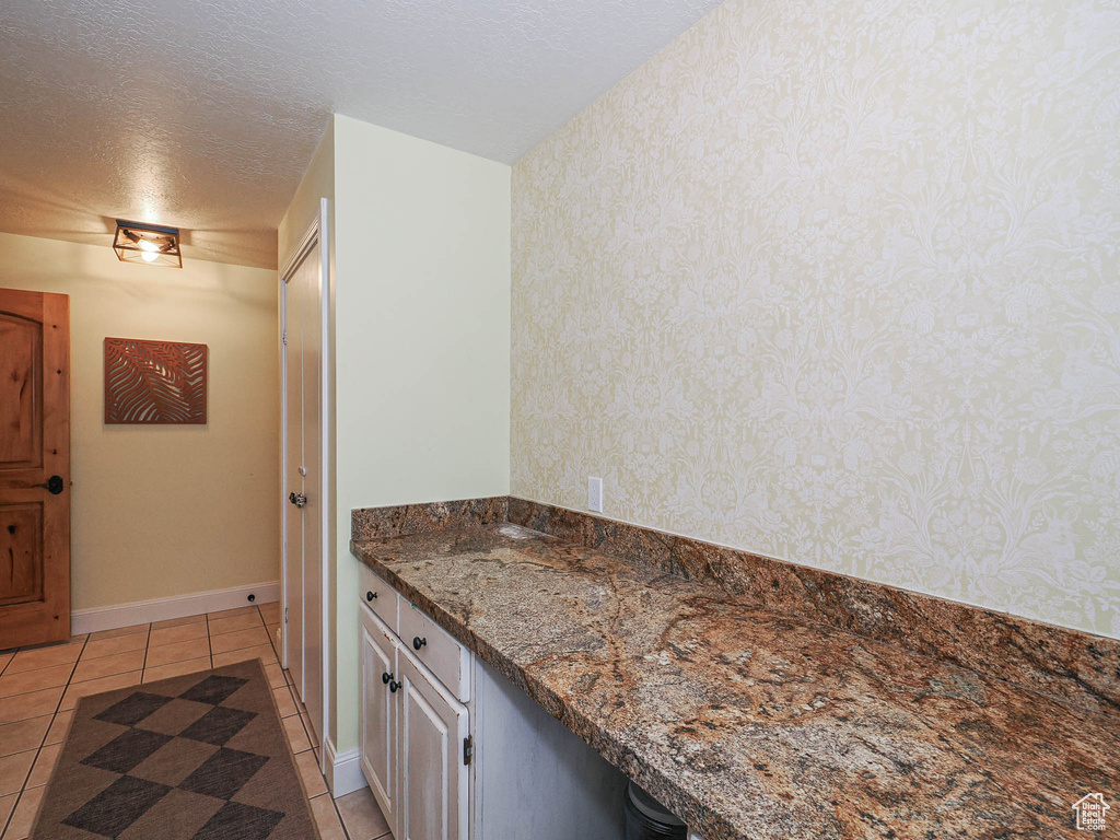 Bathroom with tile patterned flooring, wallpapered walls, and a textured ceiling