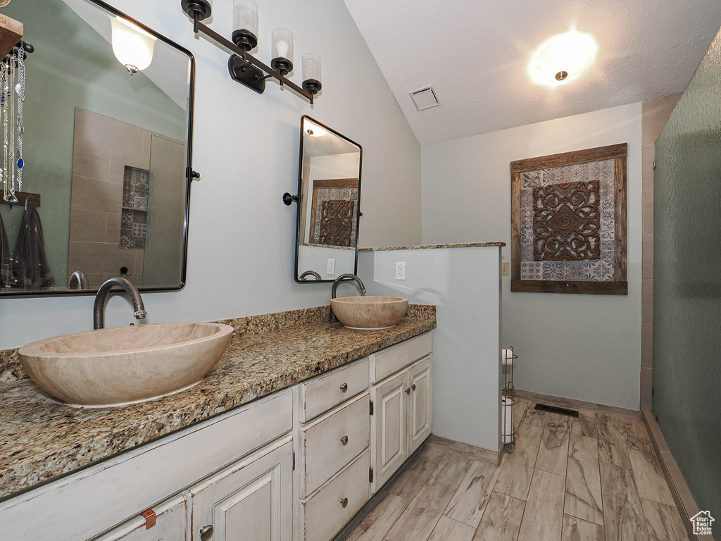 Full bathroom featuring a sink, vaulted ceiling, double vanity, and visible vents