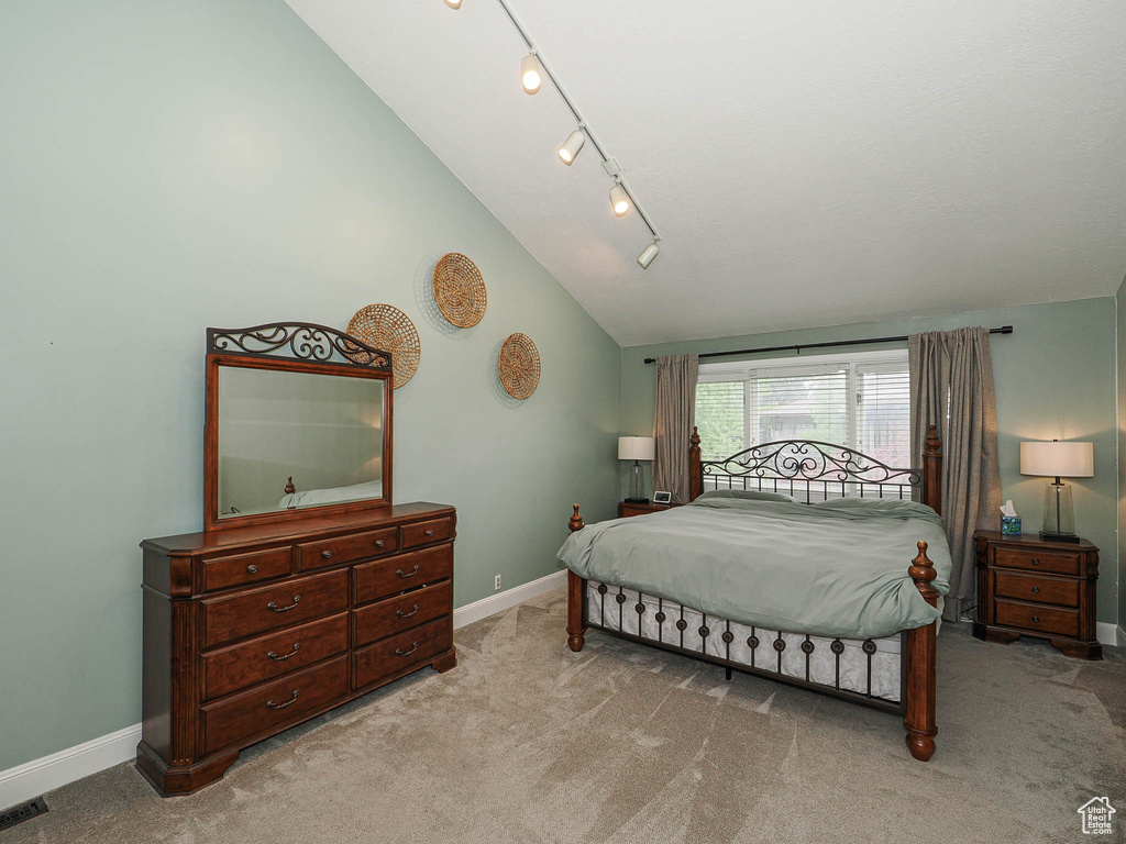 Bedroom featuring baseboards, carpet, rail lighting, and lofted ceiling