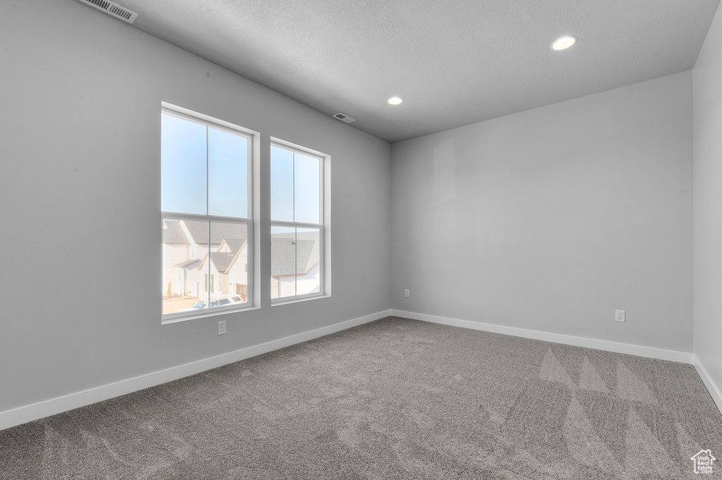 Carpeted spare room with recessed lighting, a textured ceiling, baseboards, and visible vents
