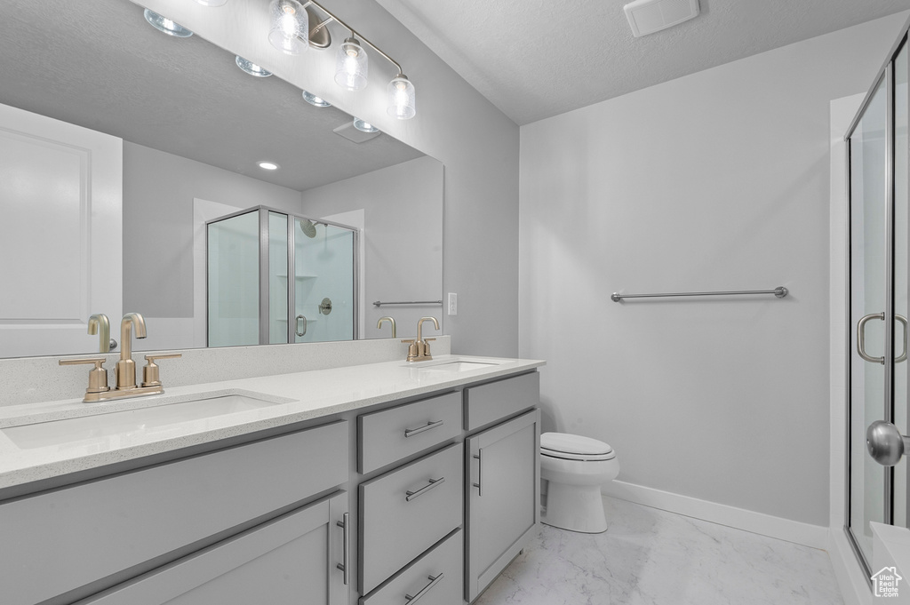 Full bath featuring a sink, a shower stall, double vanity, and marble finish floor