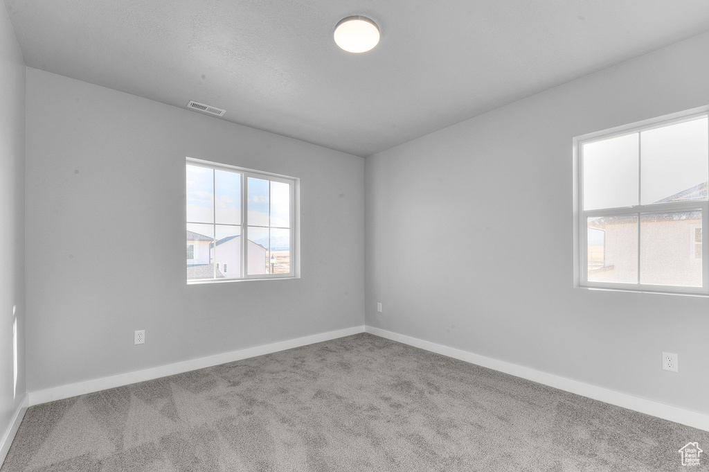 Carpeted spare room featuring visible vents and baseboards