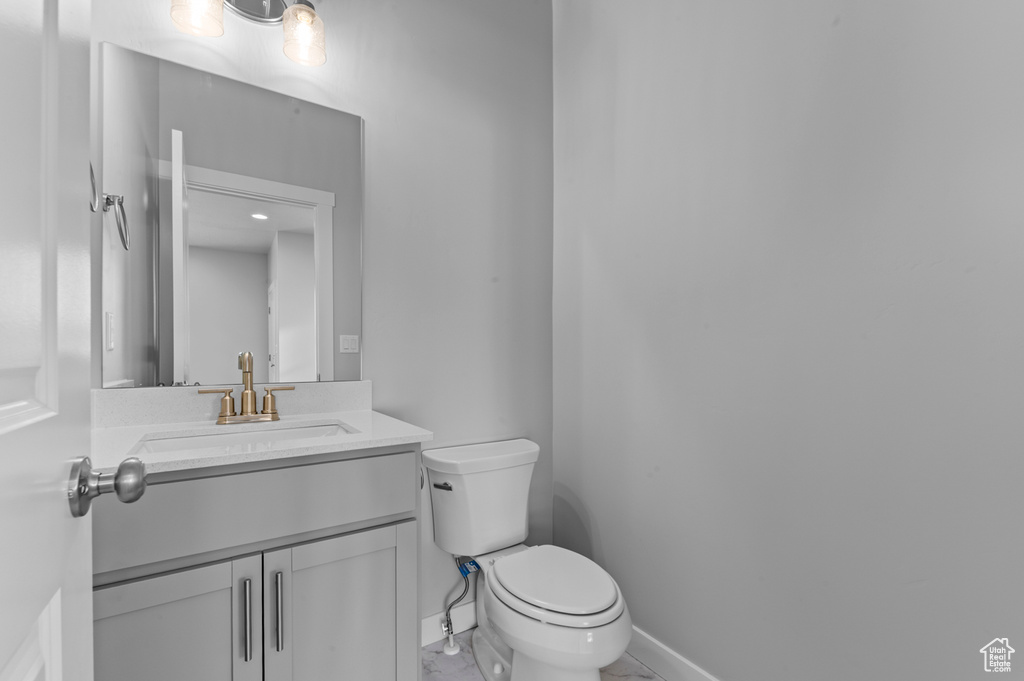 Bathroom featuring toilet, baseboards, and vanity